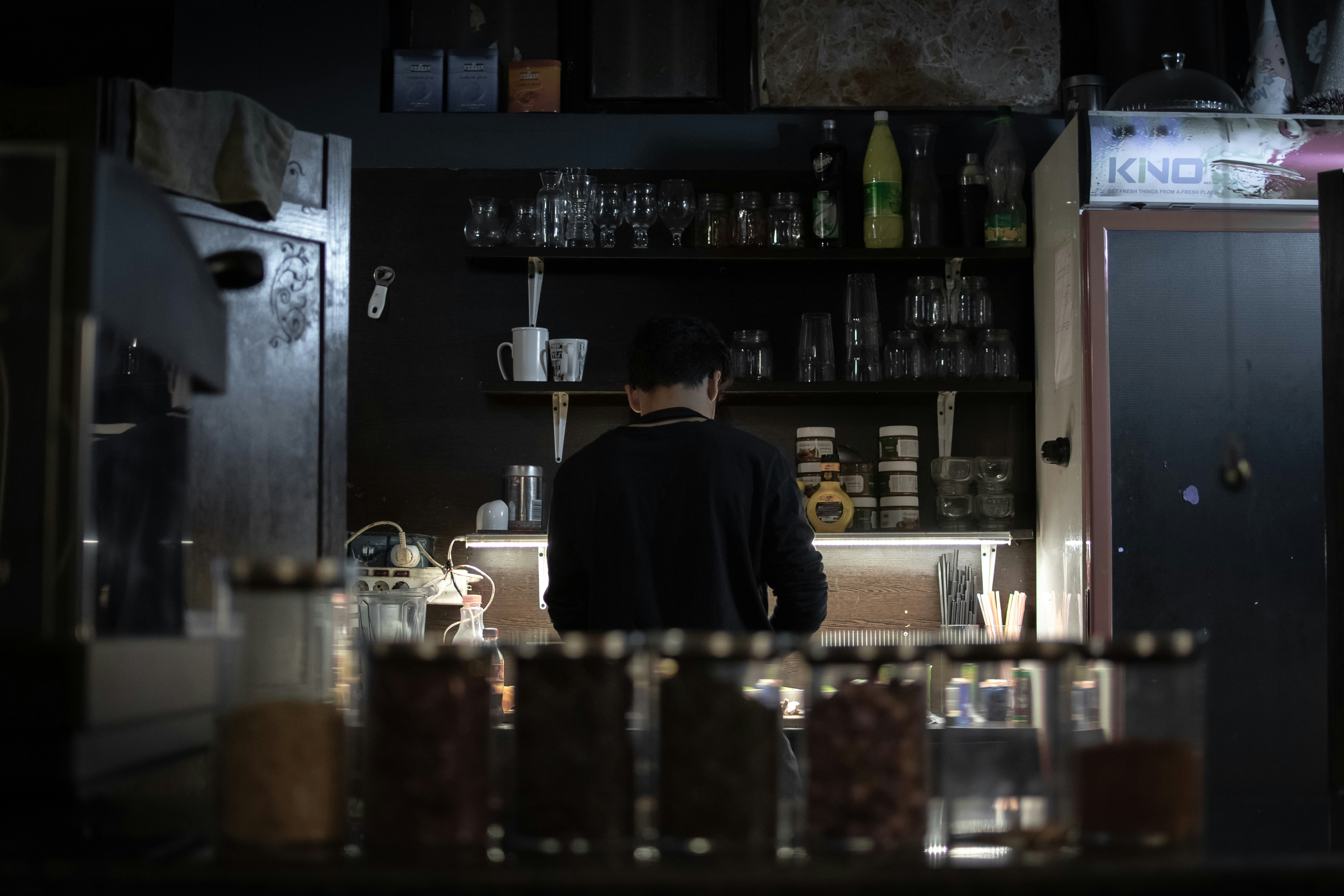 hombre de espaldas en una cocina oscura cocinando