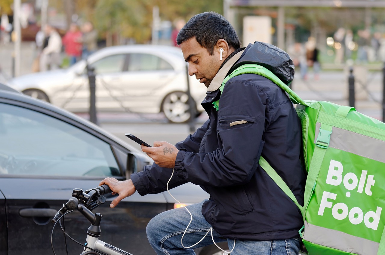 repartidor de comida a domicilio montado en una bicicleta revisando el teléfono